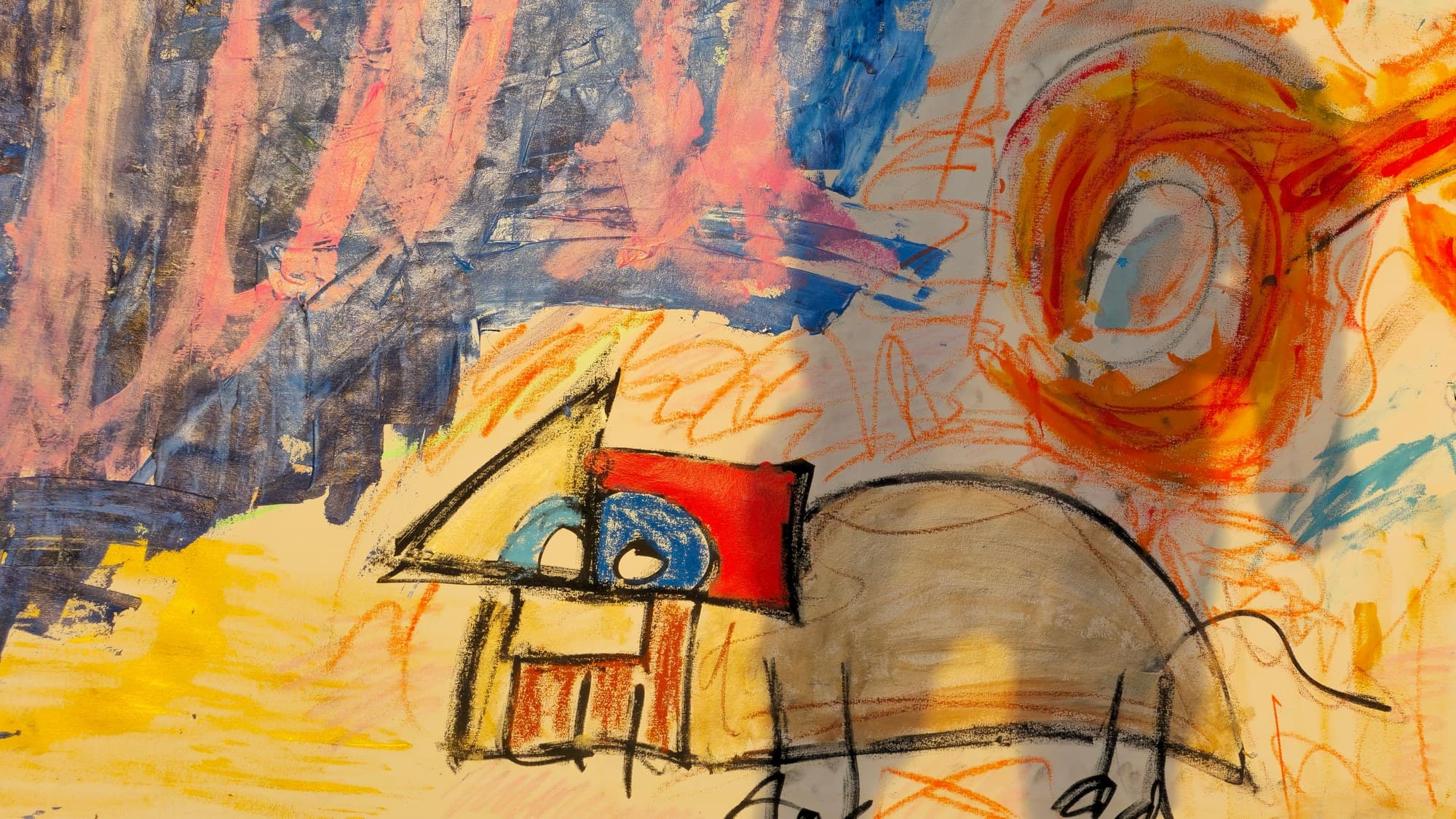 Close-up of the lower-left passage of A Pack of Lips: the beige mound-creature's back and black whisker-lines at left, a large orange coil-eye with a pale center, red and orange crayon scribble around it, and the tip of a green daisy entering from below against sky blue.