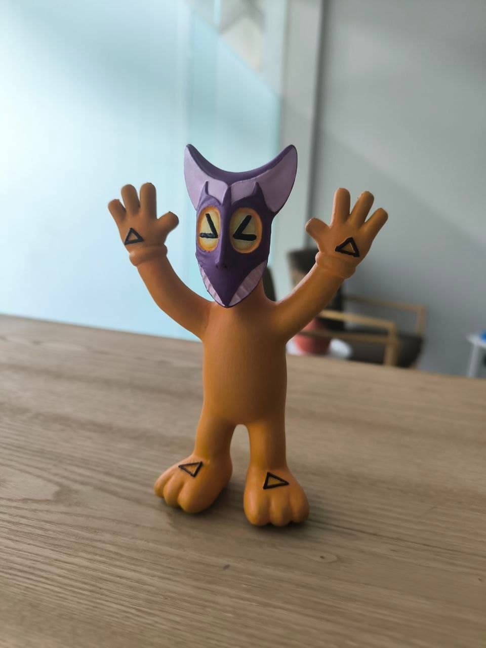 Finished painted Apophis prototype, front view: orange body with raised hands, black triangle markings on hands and feet, purple horned mask face with yellow eyes.